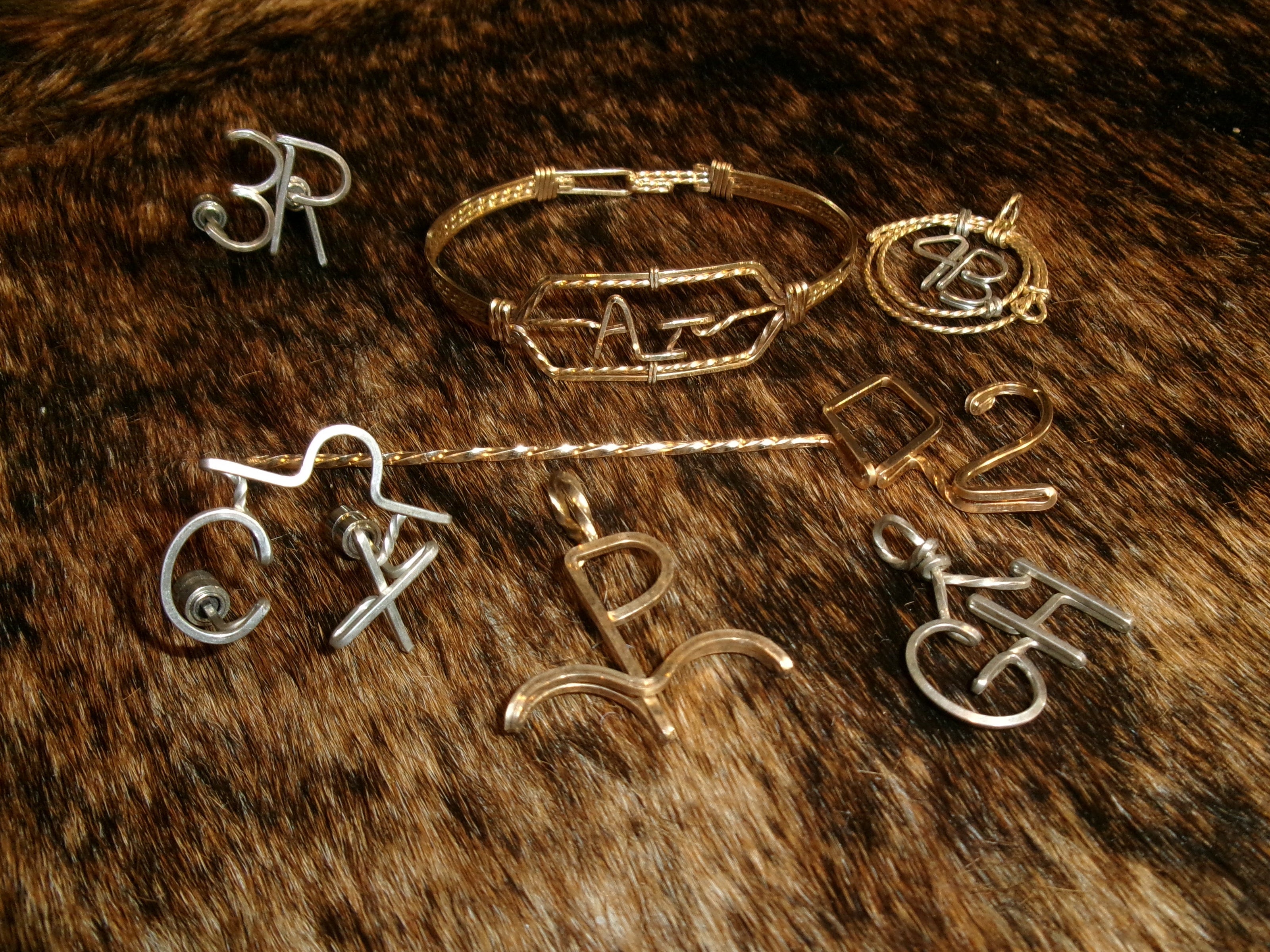 Collection of jewelry items, including a bracelet, hat pins, pendants, and a toothpick on a fur surface.