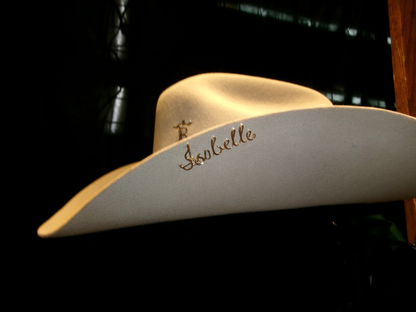Beige cowboy hat with ‘Isabelle' on a dark background
