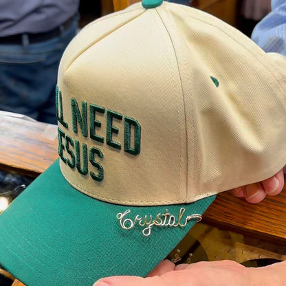 Beige cap with green text and brim held by a person in an indoor setting